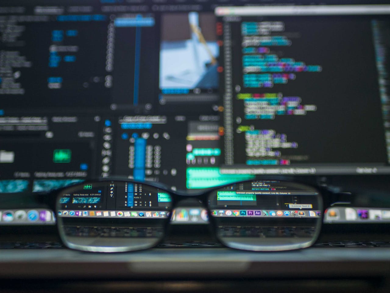 Code reflected in glasses in front of a monitor.